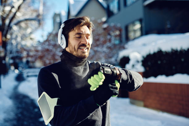 Happy athlete using smart watch while jogging on snowy street.