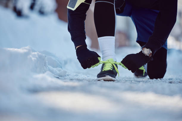 istock Close up of runner tying shoelace while jogging in snow. 1458892067