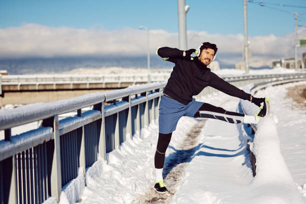 istock Athletic man stretching his leg while exercising outdoors in snow. 1458892796