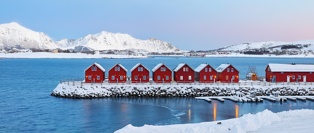 Gorgeous scenery wit traditional red wooden houses on the shore of Offersoystraumen fjord. Popular travel destination on Lofotens. Location: Vestvagoy island, Lofoten; Norway, Europe