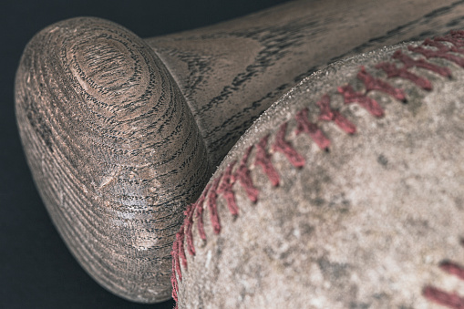 Extreme close-up of a wood baseball bat and a well used baseball.