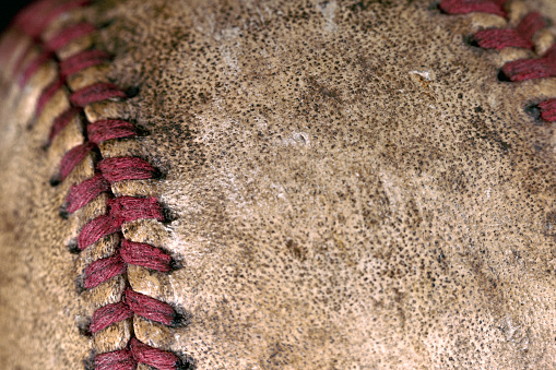 Extreme close-up of a vintage baseball with red stitching.