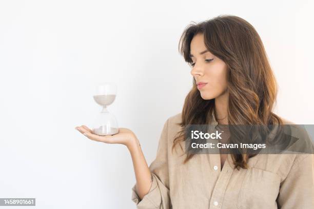 Young Woman Looking At An Hourglass Stock Photo - Download Image Now - 30-34 Years, Adult, Adults Only