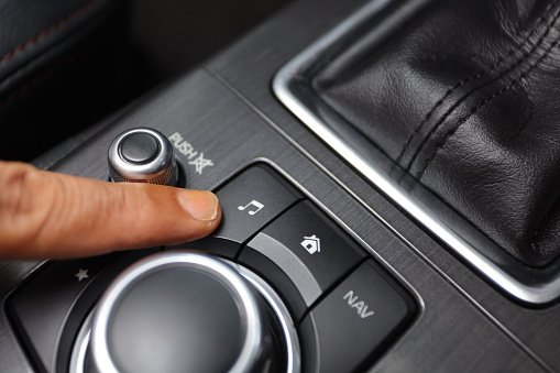 driver's finger pressing the music button.  in-car entertainment features