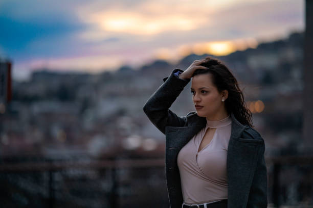 Cool young girl in autumn coat illuminated by neon lights at night.