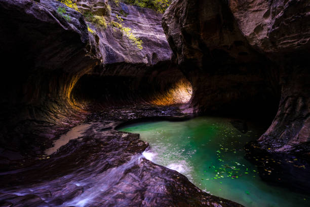 The end of the subway tunnel in Zion National park with emerald pools and light coming in from the end of the tunnel