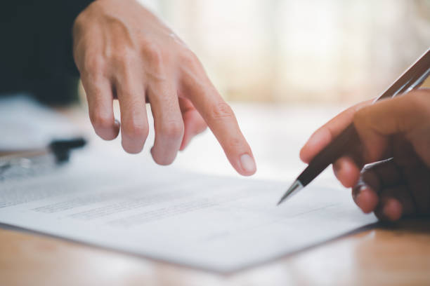 istock real estate agent pointing at document for client to sign,Managing documents and business deals , signing a business contract ,Contract approval or warranty documents, Company successful contract management 1458949563