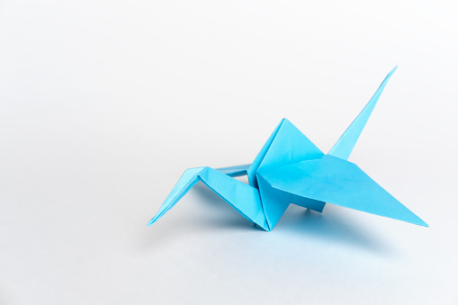 Traditional Japanese origami cranes made of blue paper on a white background. Children's creativity. A symbol of peace.
