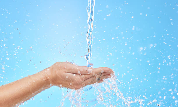 istock Hand, water and cleaning with a splash in studio on a blue background for hygiene or hydration. Mockup, health and wellness with a female washing under a water splash in the bathroom for skincare 1458958645