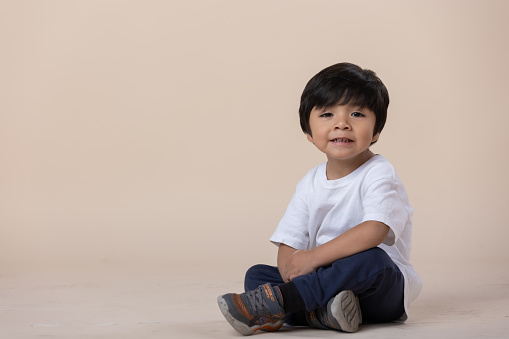 Mexican little boy sitting on the floor, looking at camera