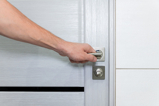 Man closes or opens the door to the room. Metal door handle and latch. Lock the bathroom door.