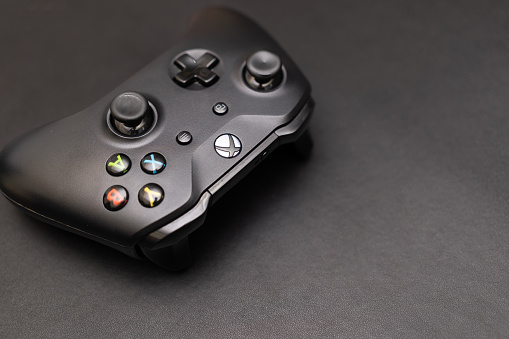 Wireless gamepad for the Xbox One on desk with keyboard. Black Xbox game controller.