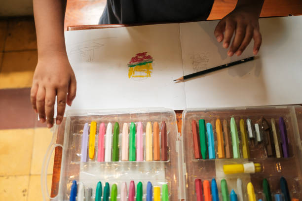 istock a top view of an asian boy while he is drawing using his crayons and pencils on the table, Science, Technology, Education, Mathematics or STEM concept 1458983132