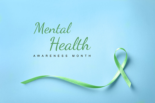 World Mental Health Day. Green ribbon on light blue background, top view