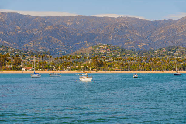 santa barbara harbor, california. boat on a water, beautiful beach with palm trees,  mountains, and cloudy sky on background - sea commercial dock harbor bay imagens e fotografias de stock