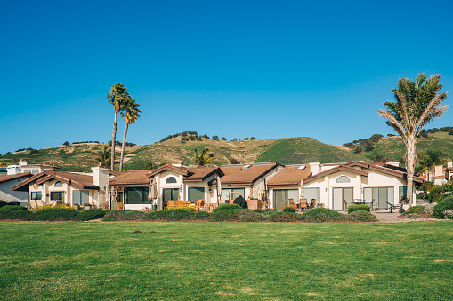 Beautiful houses with nicely landscaped front the yard and clear blue sky on background in a small beach town in California.