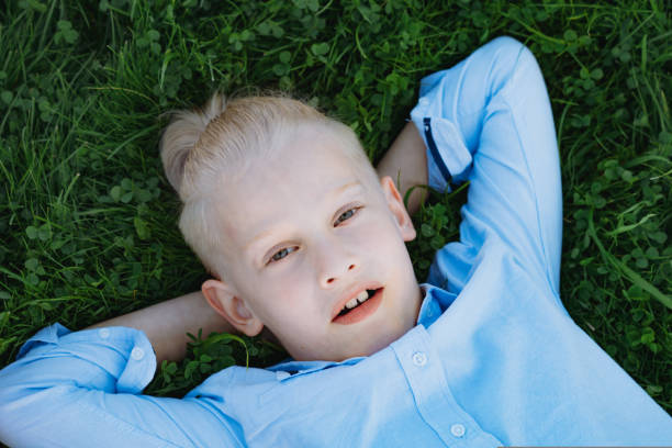 Portrait of beautiful little white boy in cap in green summer park on sunny day