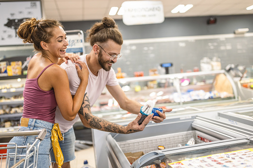 Shot of young couple shopping in the refrigerated or freezer section of a supermarket.
