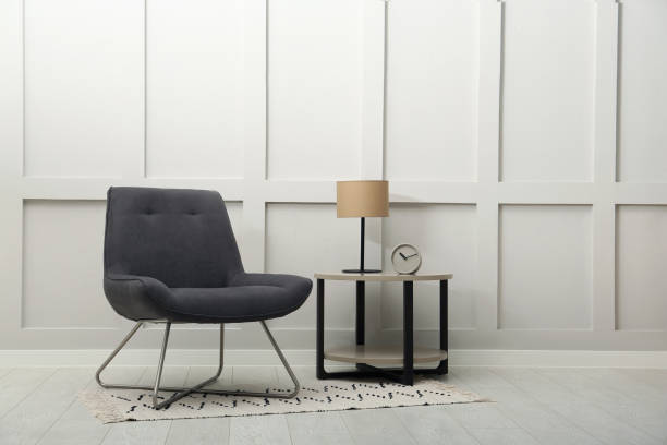 istock Modern grey armchair and small table near white wall indoors. Space for text 1458986946