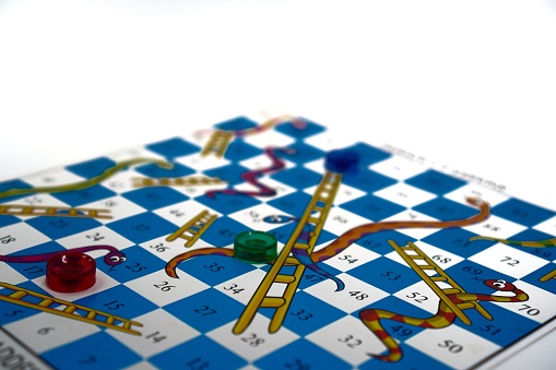 Image showing a demonstration of playing a snakes and ladders board game for leisure time relaxation on a white background.