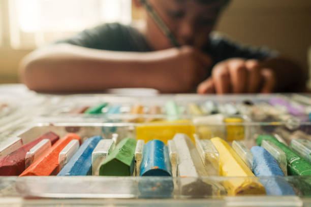 istock selective focus of lined crayons owned by an asian boy while he is drawing using his crayons and pencils on the table, Science, Technology, Education, Mathematics or STEM concept 1458993766