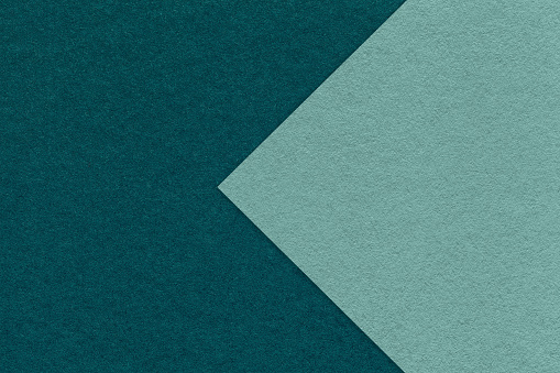 Texture of dark emerald paper background, half two colors with cyan arrow, macro. Structure of dense craft teal cardboard. Felt abstract backdrop closeup.