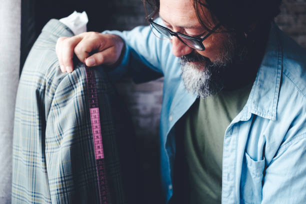 istock Tailor man at work taking measures on garment in the workshop. Alternative job. People in handmade working activity. Side view of professional worker working happy alone. Fashion industry concept 1458997079