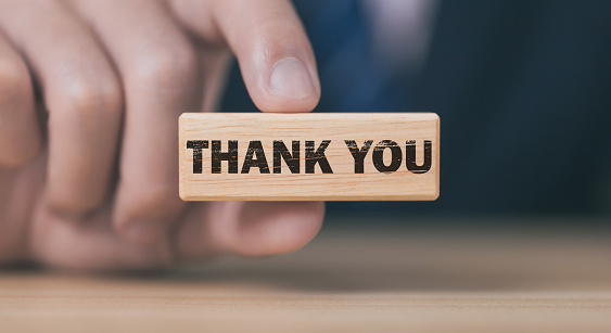 Businessman holding a wooden block showing thank you message
