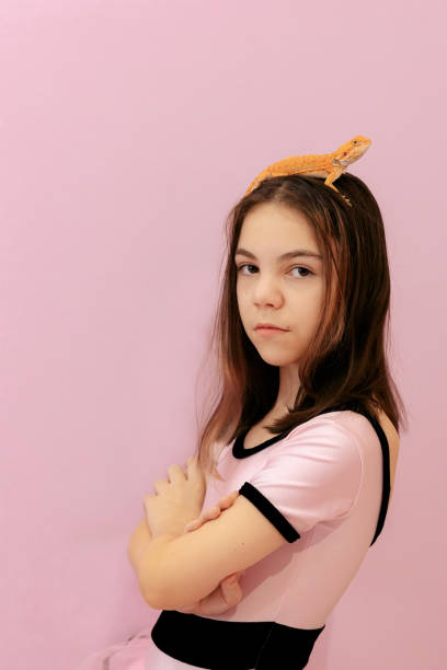 portrait of pretty girl with red bearded agama iguana on pink background. little child playing with reptile. selective focus. - iguana reptile smiling human face imagens e fotografias de stock