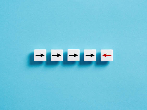 istock Different thinking, individuality and standing out from the crowd. Diversity, opposition or confrontation. Arrows on white blocks in a row with one arrow pointing the opposite direction. 1459008478