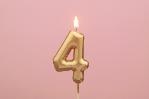 Burning gold birthday candle on pink background, number 4