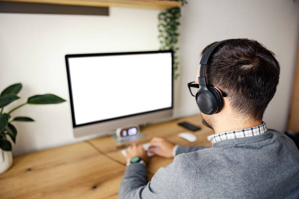 istock Back view of a man with headphones types on keyboard and working from home office. 1459014828