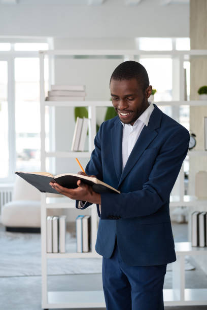 istock Smiling African American businessman wearing formal suit standing taking notes 1459015087