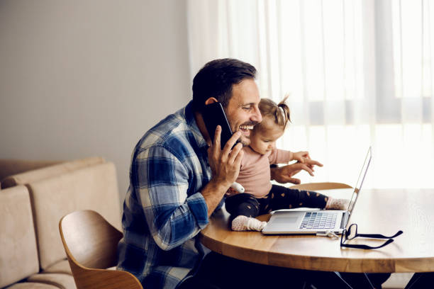 istock A busy stay-at-home father is having phone call form work while smiling at the laptop. 1459015343