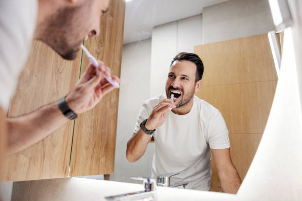 istock A morning man is looking himself in the mirror in bathroom and brushing his teeth. 1459015937