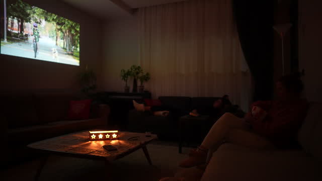 Woman with son watching home cinema projection in the living room at home.