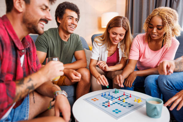 Friends having fun playing ludo board game at home stock photo