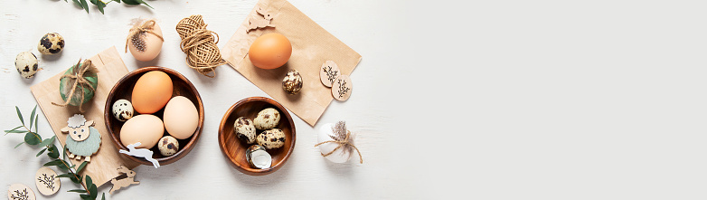 Easter eggs decorated with natural materials on a white background. Top view. Minimalistic decor for Easter. Panorama with copy space.