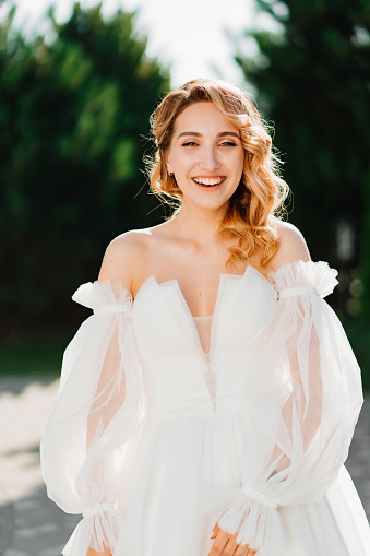 a happy beautiful blonde bride in a white dress at sunset. the concept of women's happiness and confidence. professional makeup and cosmetics for weddings