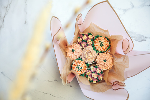 Cupcake decorated with white various colors flower icing isolated on white background. Shoot from top. Floral bouquet. Wedding cupcakes. Mothers Day,Birthday, Valentine Holiday Romantic