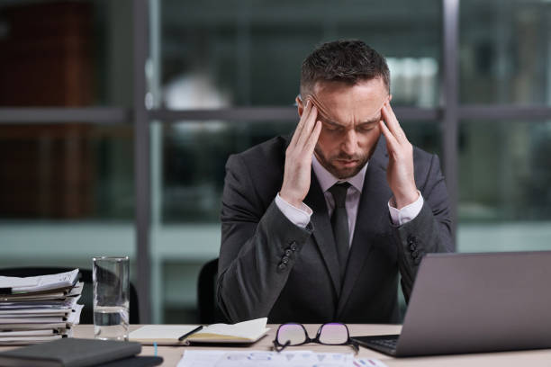 istock Tired and stressed male broker touching temples while bending over workplace 1459028165