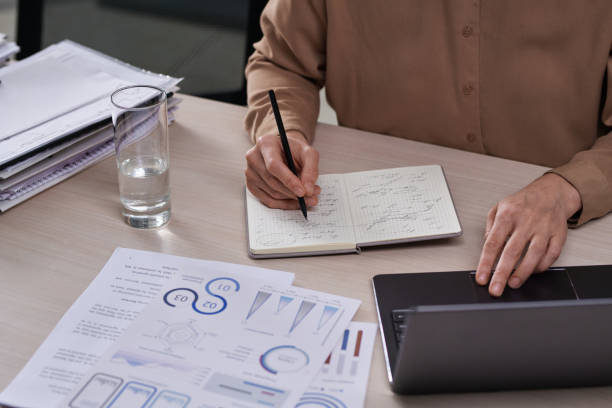 istock Close-up of hands of female entrepreneur making notes in notebook 1459028864