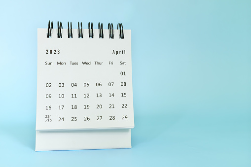 Selective focus of April 2023 desk calendar on blue background with copy space.