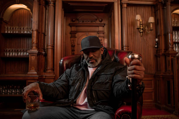 A handsome elegant 1920s style black gentleman in a luxury drawing room with a chesterfield sofa