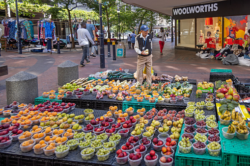 Cape Town, South Africa - December 10th 2022: Customer in a open air pop-up greengrocers shop on a street corner in the pedestrian zone in the center of the town