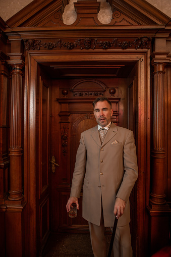 A handsome elegant 1920s style gentleman in a luxury stately home