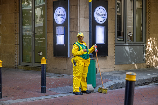 Cape Town, South Africa - December 10th 2022: Young female street sweeper in a yellow fancy uniform