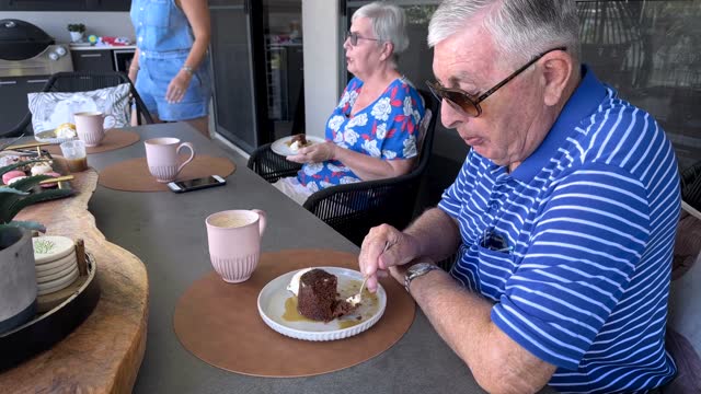 Senior couple sharing cake and coffee together with daughter.
