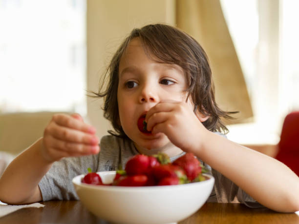 istock Cute kid eating strawberries 1459037579