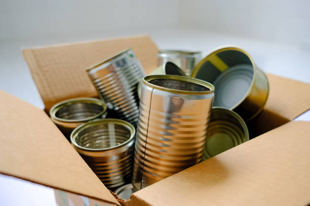 istock Close up: recycling metal tin cans. Sorting household waste into brown carton box container. Zero waste sustainability concept. White background. Selective focus. 1459038012